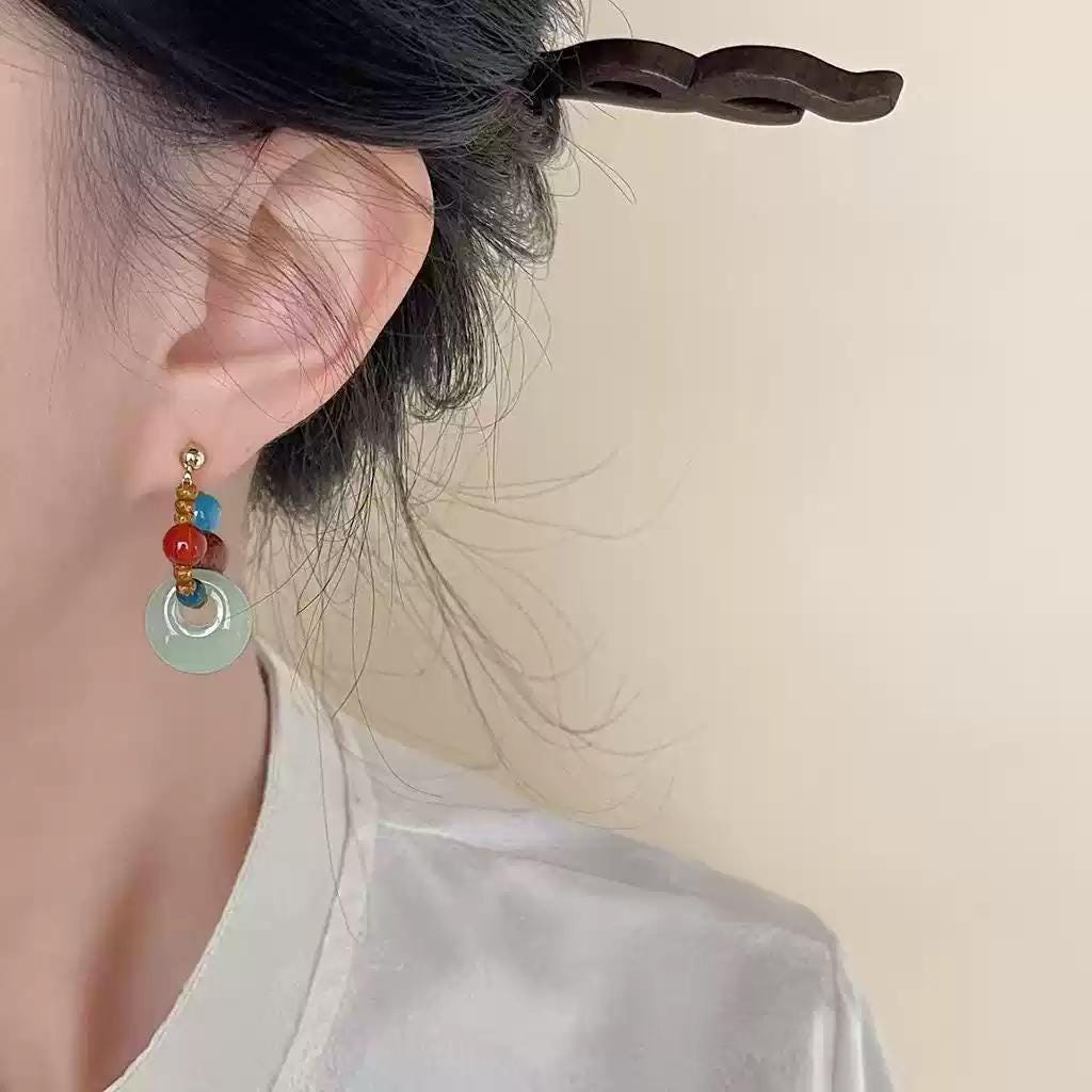 Close-up of handmade aquamarine and red agate earrings on model